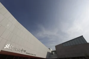 北港文化中心，仰望弧形石材外牆鑲嵌中英文館名，藍天白雲映襯