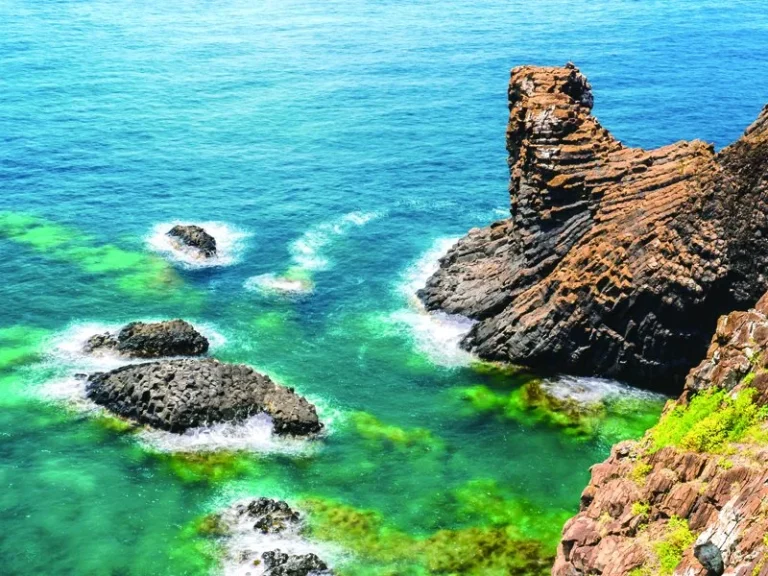 七美嶼海岸，碧綠海水拍打黑色礁岩與紅褐色節理岩柱