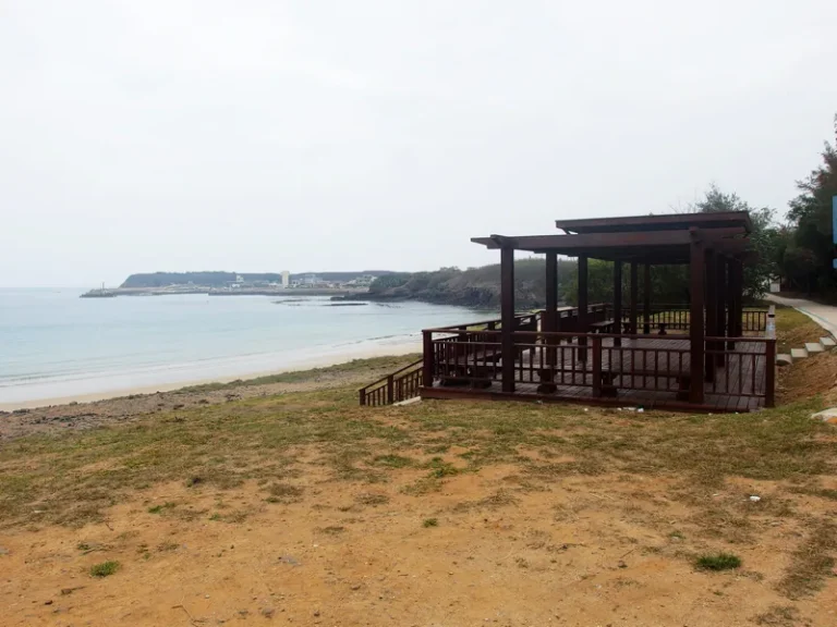 夢幻沙灘海岸旁設有木造涼亭，遠方岬角與漁村相望