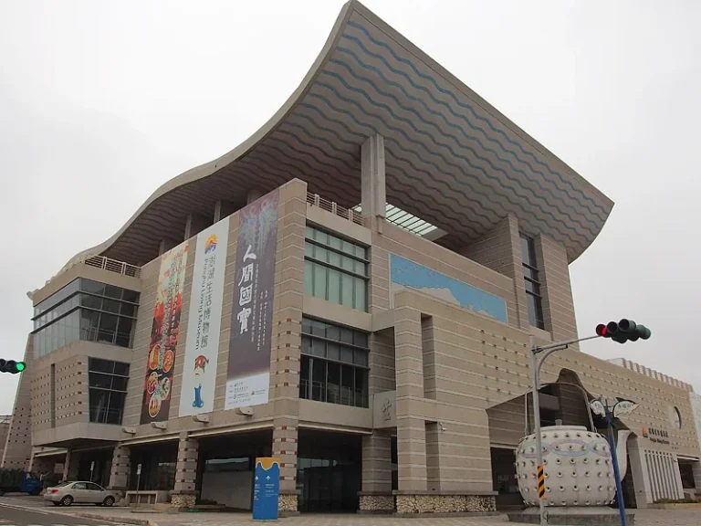澎湖生活博物館，曲線飛簷的米色石材建築外觀與懸掛展覽布條