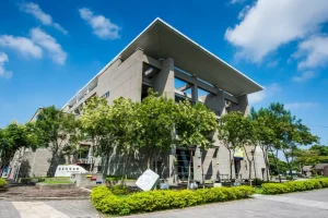 嘉義市立博物館，三角斜頂的灰色清水模建築側面與庭園綠樹