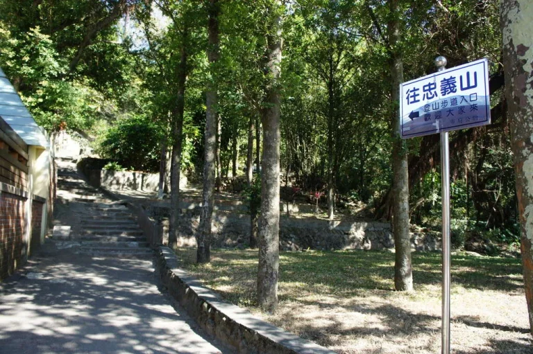 忠義山親山步道，林間石階步道旁立著「往忠義山」藍色指標牌