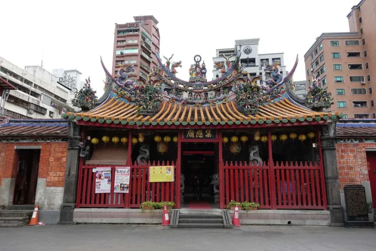 景美集應廟，紅柵欄門與彩飾屋脊矗立於現代高樓環繞的街區