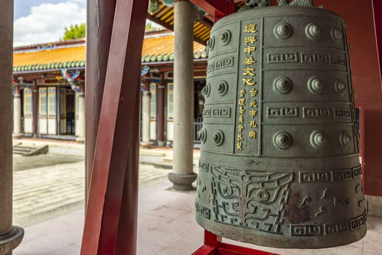 臺北市孔廟，廡廊間懸掛刻字青銅古鐘，遠處橙瓦殿宇相映