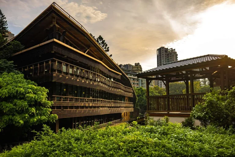 臺北市立圖書館北投分館，夕照下木造綠建築與木構涼亭掩映綠意