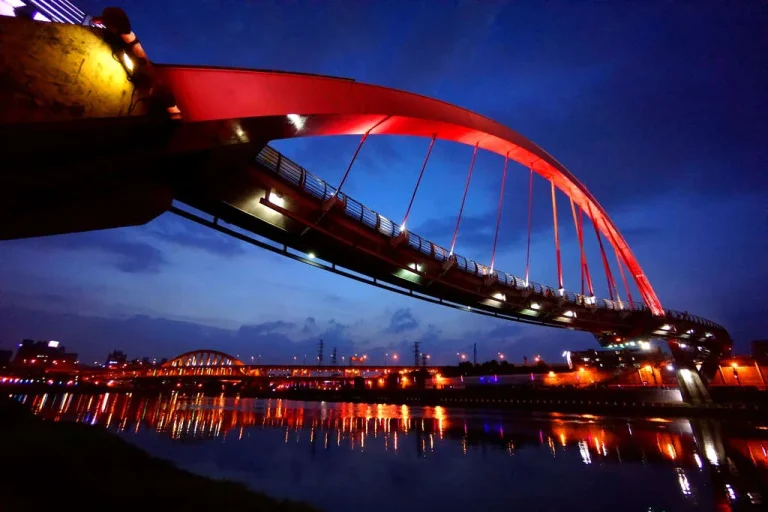 彩虹橋，夜色下亮起紅燈的拱形人行橋倒映基隆河面