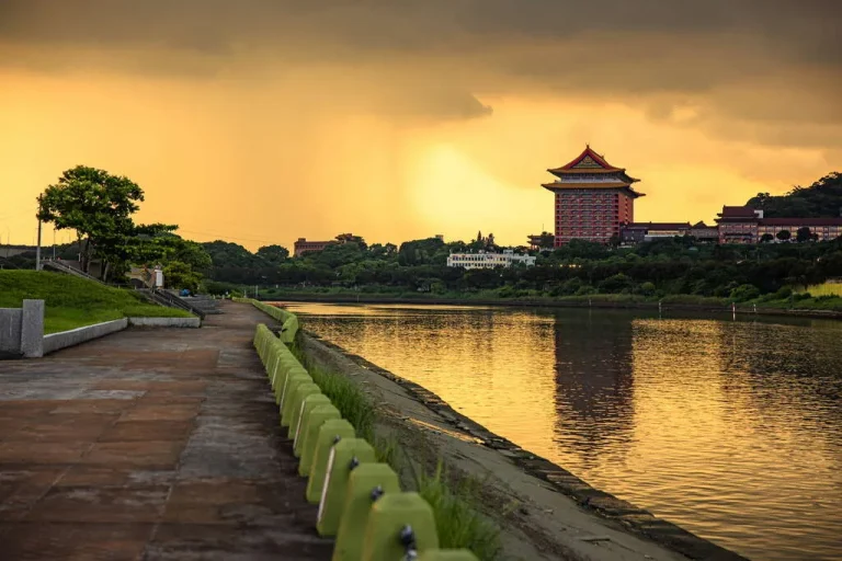 大佳河濱公園，夕陽染黃天空下河岸步道遠望圓山飯店