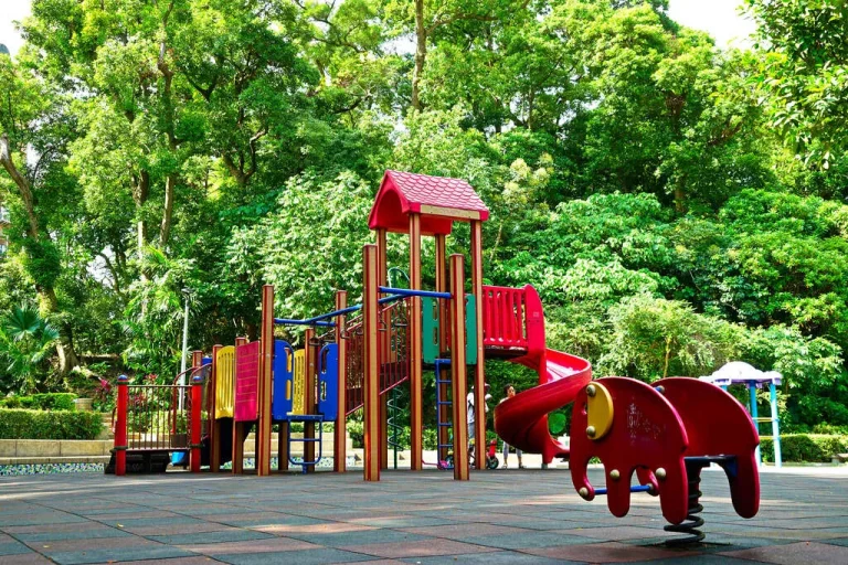 仙岩公園兒童遊戲場，綠樹環繞的彩色溜滑梯與紅色搖搖椅