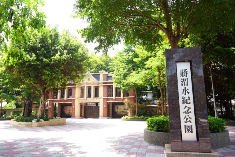 臺北市蔣渭水紀念公園，園區紅磚洋樓建築與刻字石碑及綠樹環繞
