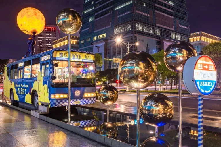 臺北市幾米月亮公車，夜色中發光黃月亮與彩繪藍色公車及鏡面圓球