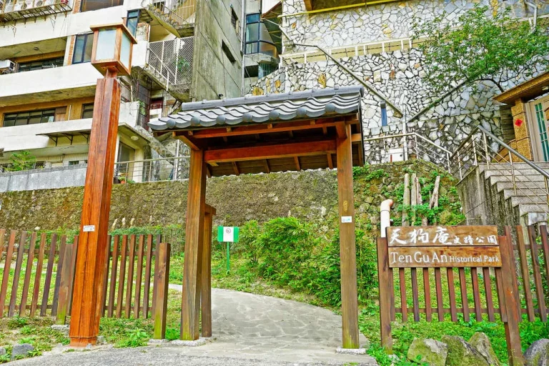 天狗庵史蹟公園，日式木造瓦頂門廊立於山坡石牆住宅旁