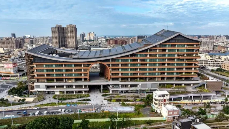 鳳山車站，弧形曲線屋頂環抱的大型站體建築，高雄市區樓房環繞