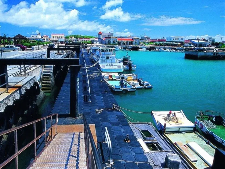 澎湖岐頭浮動碼頭，漁船停泊碧綠港灣，岸邊聚落房舍與階梯碼頭相連