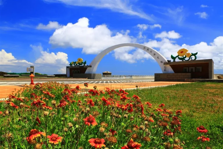 澎湖跨海大橋，藍天白雲下的白色拱門與前景盛開天人菊