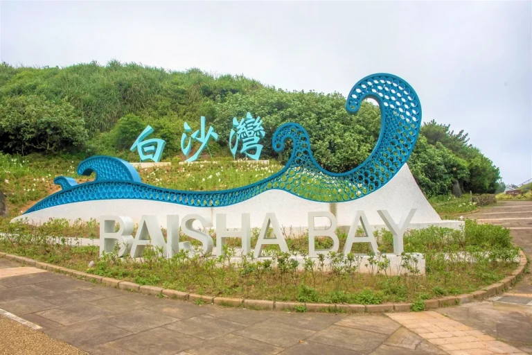 白沙灣水域遊憩區，藍色波浪造型的白沙灣地標立於綠丘下的環形步道前