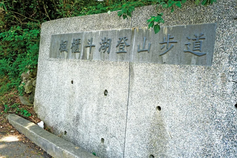 楓櫃斗湖步道，石砌台座上刻著步道名稱的指示標，旁有綠樹草叢