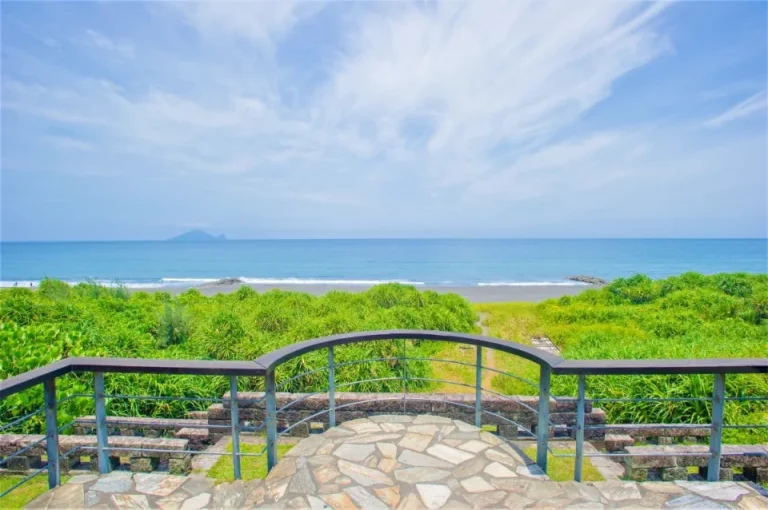 永鎮濱海遊憩區觀景平台，弧形欄杆外是蔚藍海面與遠方龜山島