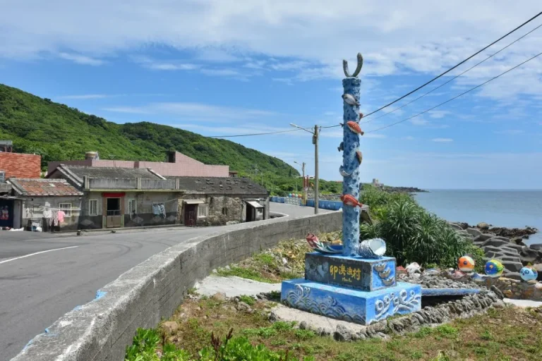卯澳灣，海濱公路旁彩繪魚群圖騰柱矗立，老石屋聚落臨海而建