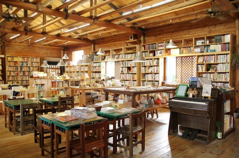 晴耕雨讀小書院，木造屋內成排書架與長桌椅環繞著一台舊風琴