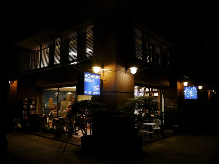 梓書房，夜色中亮起燈光的二手書店街角，藍色招牌與門前綠植